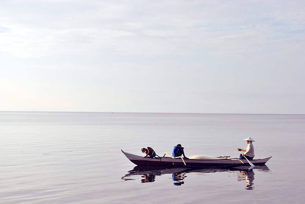 Three fishermen on a boat on the open sea.