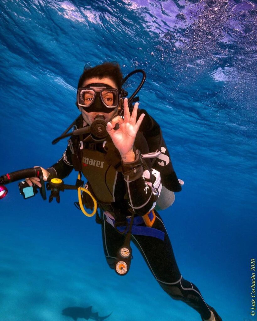 Underwater photographer signaling OK while diving with a camera and lighting setup